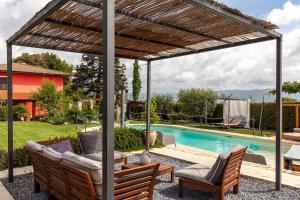 eine Pergola mit zwei Stühlen und einem Tisch neben einem Pool in der Unterkunft l' Acciuga Blu in Monte Marcello