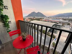 una mesa roja y sillas en un balcón con vistas en Depa Arena y Fundidora, en Monterrey