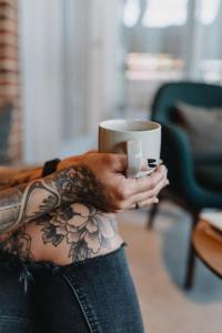 a woman with tattoos holding a cup of coffee at Südspeicher in Kappeln