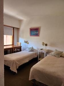 a hotel room with two beds and a desk at Hotel Barracuda in Villa Gesell