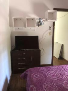 ein Schlafzimmer mit einem TV und einer Kommode mit einem Bett in der Unterkunft Gran escape! Santa Ana in Cuchilla Alta