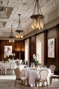 uma sala de jantar com mesas, cadeiras e lustres em The Hermitage Hotel em Nashville
