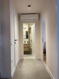 a hallway with white walls and a bathroom with a mirror at Apartament Mony in Timişoara