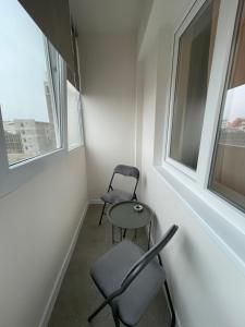 two chairs and a table in a room with two windows at Apartament Mony in Timişoara