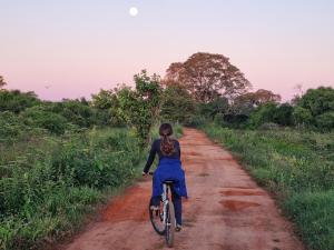a woman riding a bike down a dirt road at Aymara Lodge in Poconé