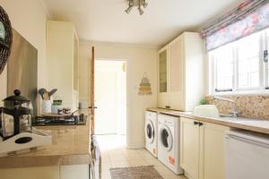 a kitchen with a sink and a washing machine at Cosy Cottage in Old Clee