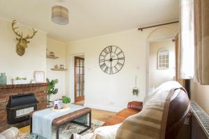 a living room with a fireplace and a clock on the wall at Cosy Cottage in Old Clee