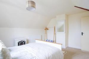a white bedroom with a bed and a fireplace at Cosy Cottage in Old Clee