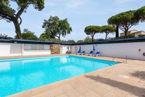 a swimming pool with chairs and trees in the background at Villa des Rives - Welkeys in Grimaud