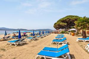 a row of beach chairs and umbrellas on a beach at Villa des Rives - Welkeys in Grimaud