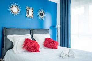 2 almohadas rojas en una cama blanca con pared azul en Le vintage - Wifi - Parking gratuit, en Monswiller