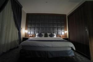 a bedroom with a large bed with a large headboard at للعائلات Suite Home at KAEC شقة بأثاث فندقي مدينة الملك عبدالله الإقتصادية in King Abdullah Economic City