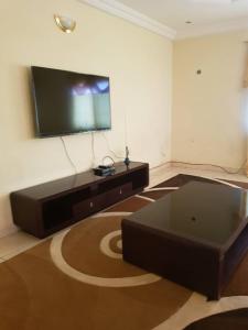 a living room with a flat screen tv and a couch at Touray Guest House in Old Yundum