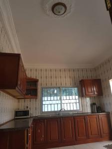 uma cozinha com armários de madeira castanha e uma janela em Touray Guest House em Old Yundum