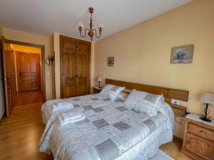 ein Schlafzimmer mit einem großen Bett und einem Kronleuchter in der Unterkunft La Nava de Gredos acogedor piso con vistas in Navarredonda de Gredos
