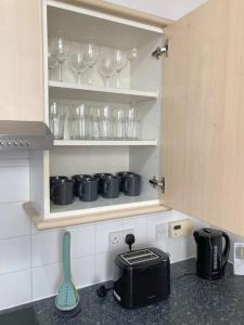 a kitchen with cups and glasses on a shelf at Spacious modern apartment. Centre of Southwell. in Southwell