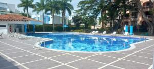a swimming pool in a courtyard with chairs and trees at Hotel Peñon Suites in Girardot