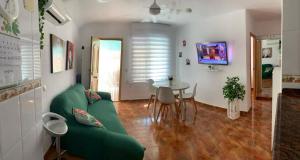 a living room with a green couch and a table at Apartamento en la playa in Tavernes de Valldigna