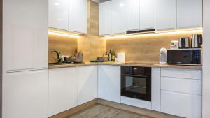 a kitchen with white cabinets and a black microwave at Charming family condo in Silver Mountain in Poiana Brasov +41 photos