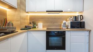 a kitchen with white cabinets and a black microwave at Charming family condo in Silver Mountain in Poiana Brasov