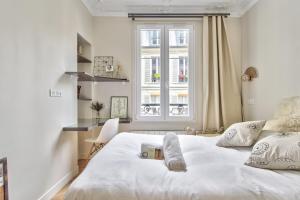 a bedroom with a white bed and a window at Beautiful flat nearby Notre-Dame & Louvre - Welkeys in Paris