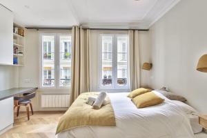 a bedroom with a bed and a desk and windows at Beautiful flat nearby Notre-Dame & Louvre - Welkeys in Paris