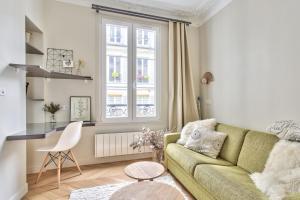 a living room with a green couch and a window at Beautiful flat nearby Notre-Dame & Louvre - Welkeys in Paris