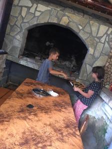 two children making pizzas in a brick oven at Vikendica RAJ in Travnik