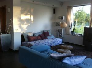 Luxury Lakefront Villa with Private Pier & Jacuzzi في بالاتونوشود: غرفة معيشة مع أريكة زرقاء ونافذة
