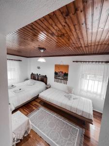 a bedroom with two beds and a wooden ceiling at The Lady of the Lake in Kalyvia