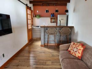 uma sala de estar com um sofá e uma cozinha em Chalé das Palmeiras em Carrancas