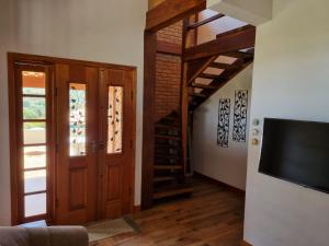 a living room with a staircase and a wooden door at Chalé das Palmeiras in Carrancas