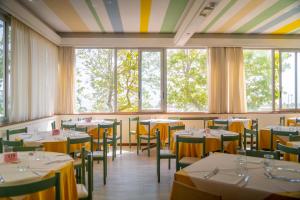 un comedor con mesas, sillas y ventanas en Hotel Royal, en Giulianova