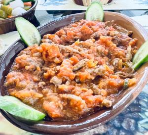 a bowl of food with meat and vegetables and lime slices at Wadi Rum Desert Camp in Wadi Rum