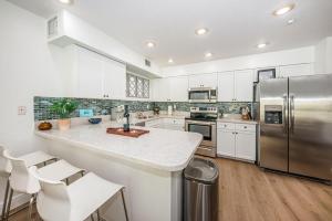 a kitchen with white cabinets and a stainless steel refrigerator at White Dunes Condo in Clearwater Beach