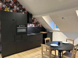 a kitchen with black cabinets and a table with chairs at Ô Colombages in Les Biolles