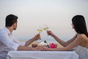 a man and woman sitting at a table with wine glasses at Hotel Villa Romana in Porto Empedocle