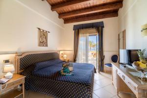 a bedroom with a blue bed and a television at Hotel Villa Romana in Porto Empedocle