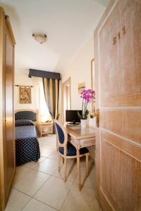 a room with a desk and a bedroom with a bed at Hotel Villa Romana in Porto Empedocle