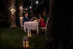 a man and a woman sitting at a table at night at Hotel Villa Romana in Porto Empedocle