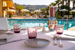 a table with plates and glasses next to a pool at Hotel Villa Romana in Porto Empedocle