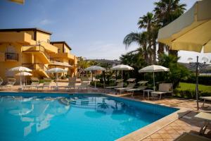 una piscina en un hotel con sillas y sombrillas en Hotel Villa Romana, en Porto Empedocle