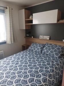 Schlafzimmer mit einem Bett mit einer blauen und weißen Bettdecke in der Unterkunft Mobil home Le Galland de Dugny in Onzain