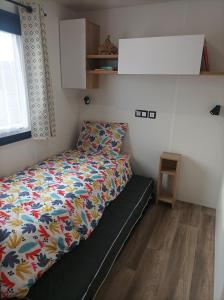 ein kleines Schlafzimmer mit einem Bett mit einer bunten Bettdecke in der Unterkunft Mobil home Le Galland de Dugny in Onzain