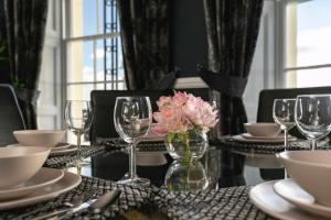 a table with glasses and a vase of flowers on it at Marine Parade Sea View 2-Bedroom Apartment in Brighton & Hove