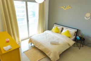 Un dormitorio con una cama con almohadas amarillas y una ventana en Himalaya Homes Lovely 1 Bedroom Apartment en Dubái