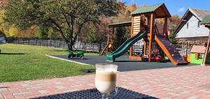 a glass of milk sitting on a table next to a playground at HAPPY TIMES in Bran