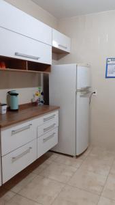 a kitchen with white cabinets and a refrigerator at Apto acochegante com Praia e lazer in São Vicente