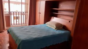 a bedroom with a blue bed and a window at Apto acochegante com Praia e lazer in São Vicente