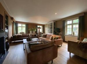 una gran sala de estar con sofás y una mesa. en Sfeervol landhuis in de groene Kempen en Baarle-Hertog